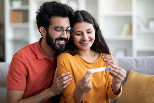 Casal sorrindo olhando para um teste de gravidez