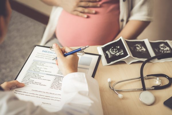 Mulher grávida em consulta com médica obstetra.