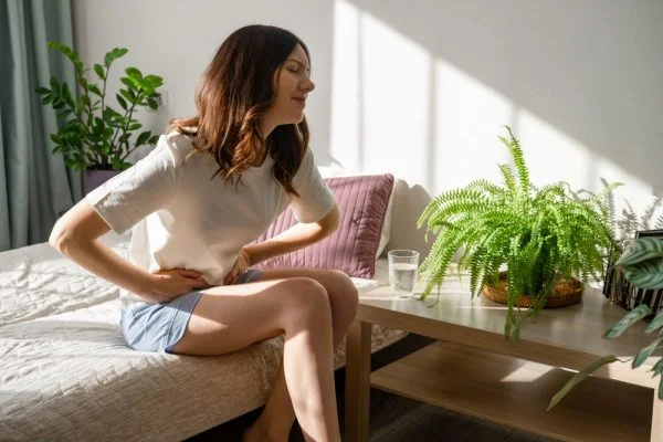 Imagem ilustrativa de mulher sentada na cama com a mão na barriga