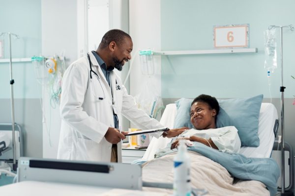 Mulher em cama de hospital sendo atendida por um médico.