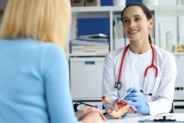 Médica em consulta com paciente mulher, mostrando um útero ilustrativo.