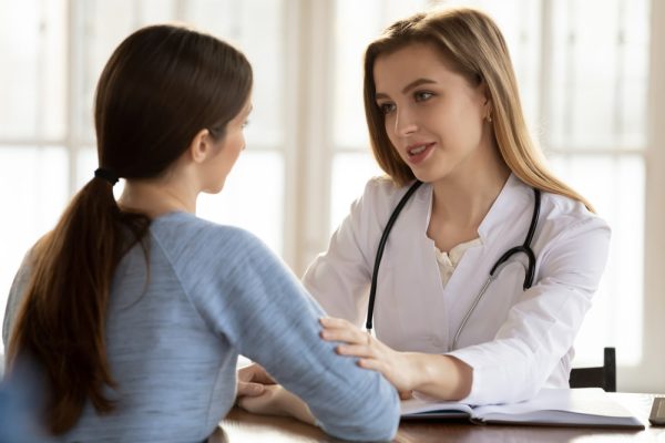 Médica conversando com paciente feminina.