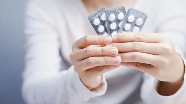 Mulher segurando cartelas de medicamento ilustrando a relação entre uso de antidepressivo e infertilidade.