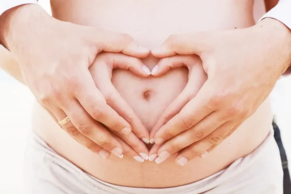 Planejamento reprodutivo: casal com as mãos formando um coração na barriga, simbolizando desejo de ter filhos