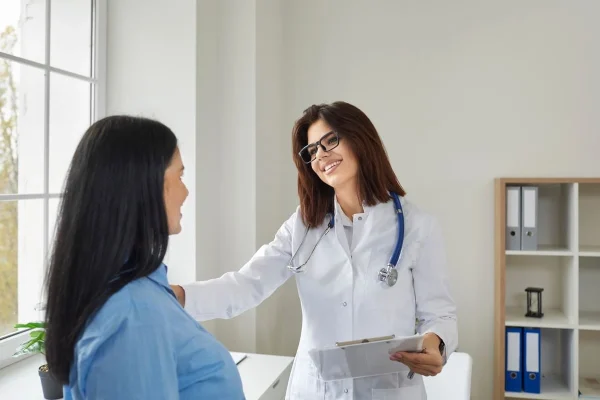 Médica sorrindo com paciente jovem representando conversa sobre idade ideal para o congelamento de óvulos.