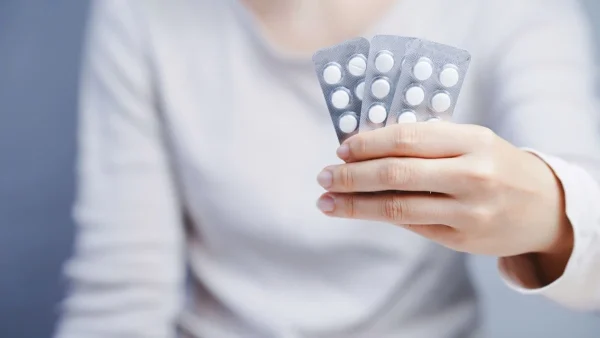 Mulher segurando cartela de comprimidos representando dúvidas se Pondera XR ou Trazodona causam infertilidade.
