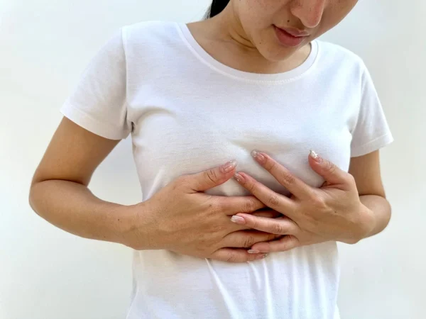 Mulher com as mãos no peito representando dor no seio depois da fertilização in vitro.
