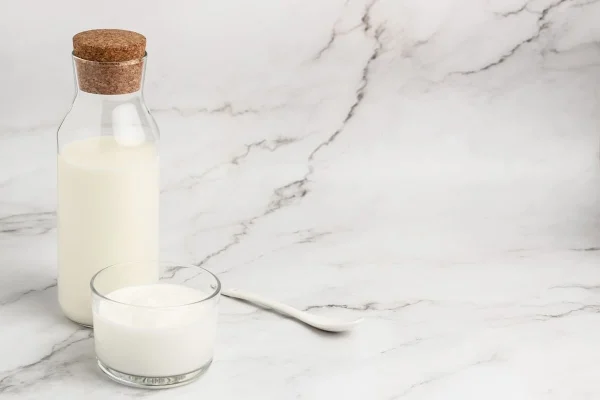 Garrafa de iogurte e copo de leite ilustrando a dúvida se lactose atrapalha a FIV.