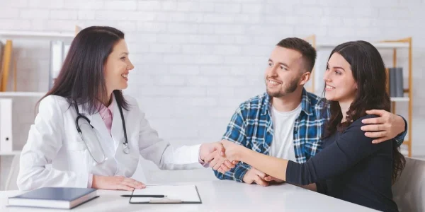 Casal satisfeito conversando com médico ilustrando a relação após a FIV.